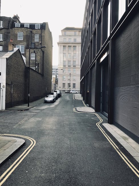 In this image, a worker wearing protective gloves and a high-visibility vest is seen loading a cardboard box into the rear of a white van parked in a designated loading bay area on Marylebone High Str